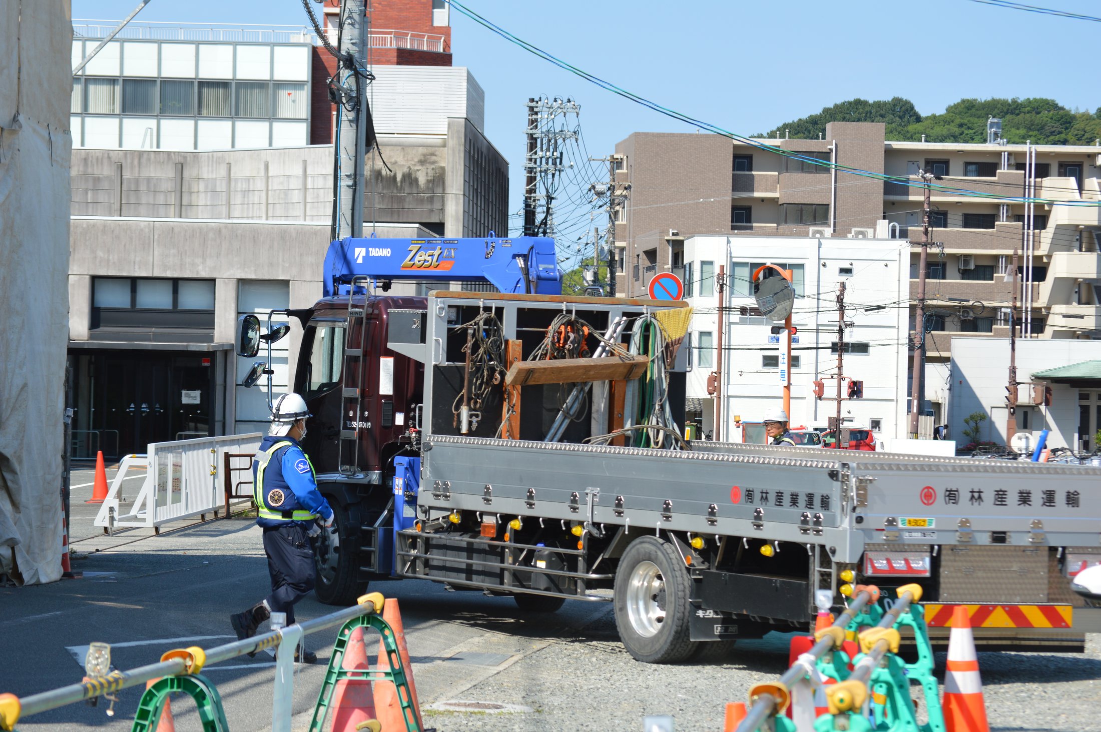 市街地の現場でユニック車を配置して作業する様子